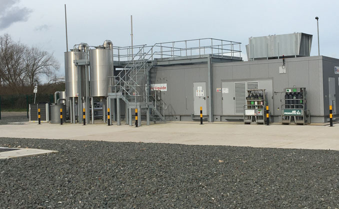 Biomethane gas injection facility with industrial equipment, storage tanks, and safety barriers on a gravel site